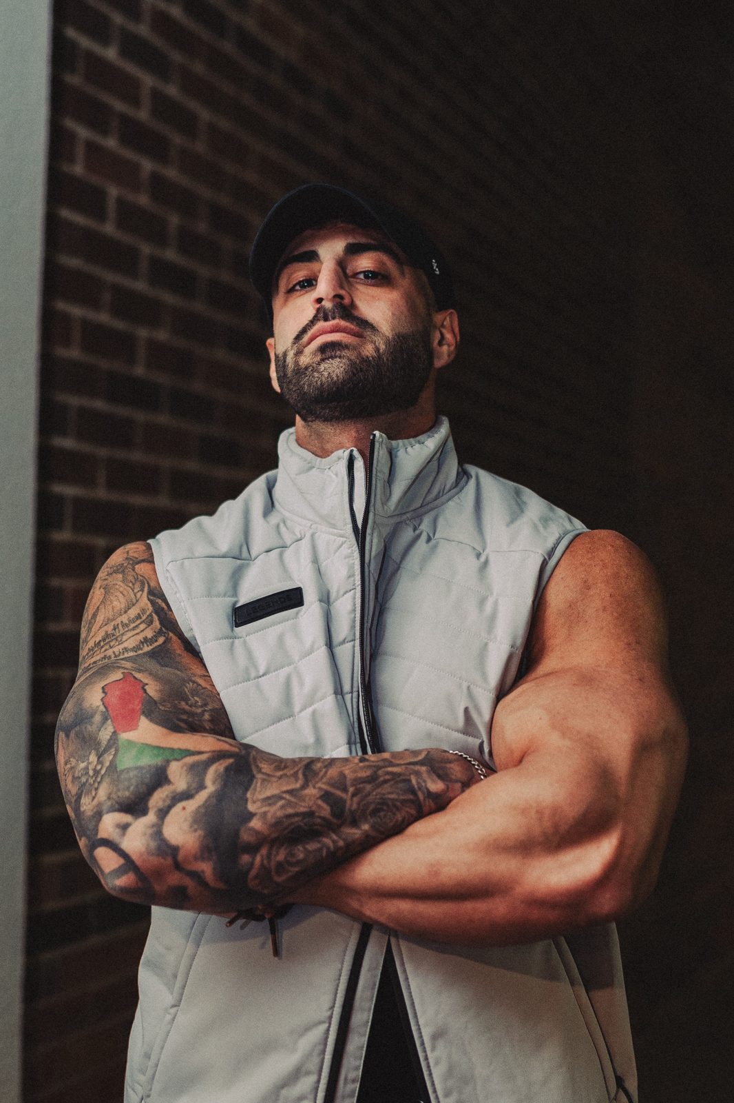 Coach portrait, arms crossed in front of a brick wall